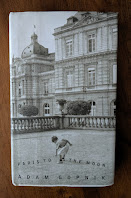 The cover shows a small boy bending over to pick up a pebble in a Parisian park.