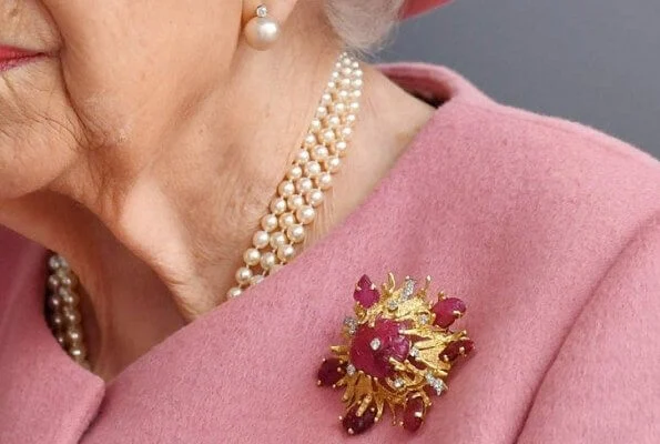 Queen Elizabeth wore a pink coat by Stewart Parvin and matching hat by Rachel Trevor-Morgan. Carved Ruby, gold and diamond brooch, Grima ruby brooch