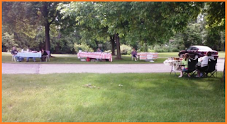 Three tables on one side of a park's path.  One table on the opposite side.