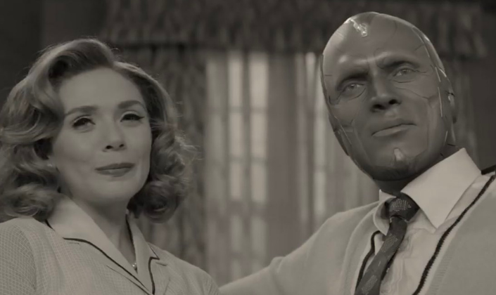 Imagem de capa: Wanda interpretada por Elizabeth Olsen e Visão, interpretado por Paul Bethany, com o rosto metálico, sem cabelos de andróide, em roupas de época dos anos 50 e em preto e branco, sentados um do lado do outro, com o fundo que parece ser as cortinas de uma casa de subúrbio.
