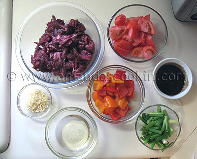 Bowls filled with all the ingredients to make beef stir fry with tomatoes and peppers.