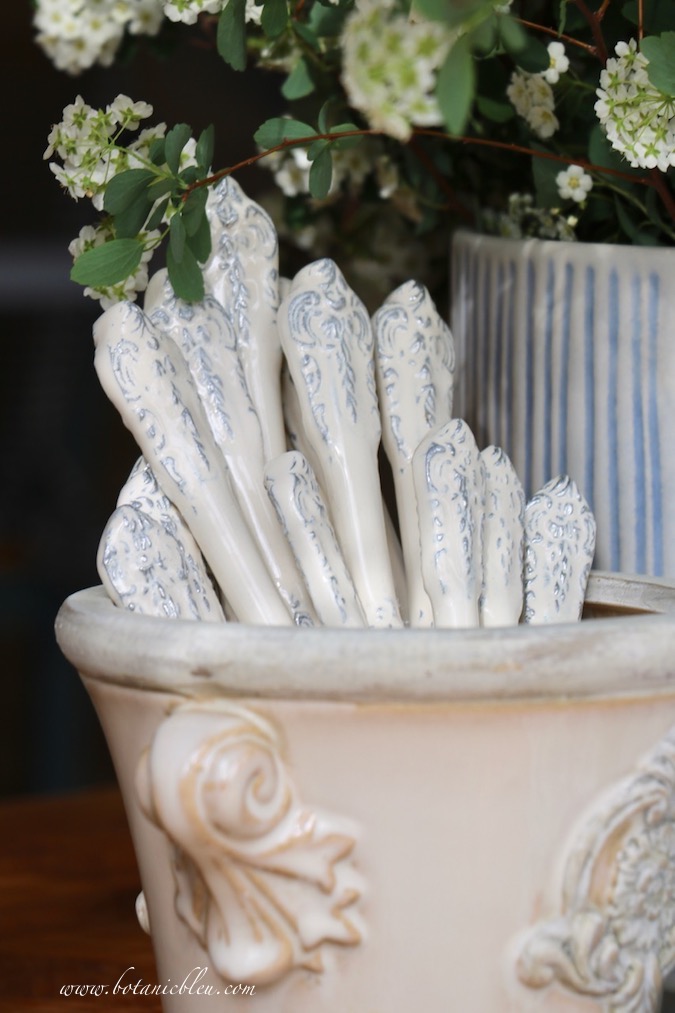 White scroll flatware in a white flower pot is a fun way to display flatware on an Easter table