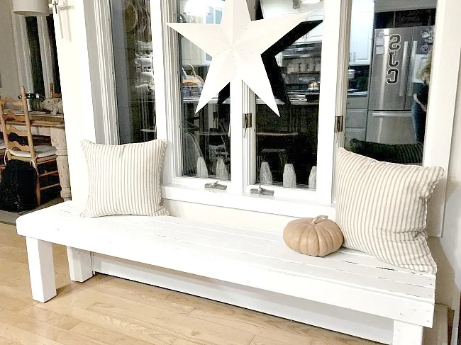 White bench under window with pillows