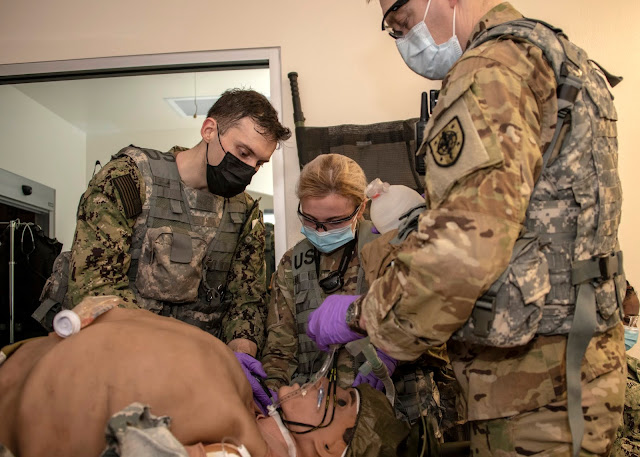 A group of students practice administering aid to a mannequin.