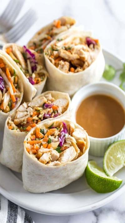 These Asian chicken wraps with peanut sauce are an easy and healthy lunch. Tortillas filled with chicken, crunch coleslaw and peanuts with a spicy, tangy peanut sauce. #chicken #lunch