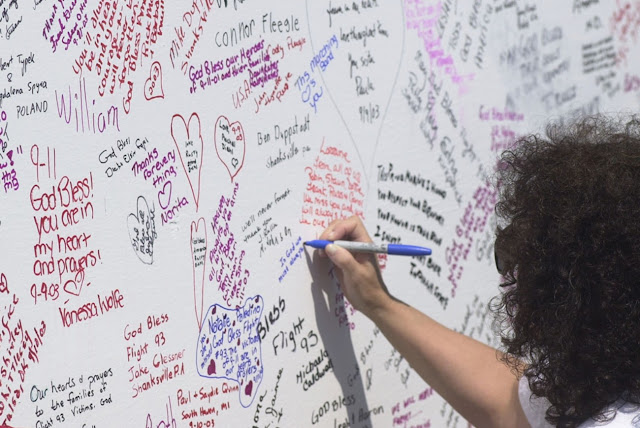 Посетитель временного мемориала событий 9/11 на месте крушения рейса 93 пишет послание погибшим пассажирам и экипажу.  Фото: Archie Carpenter/Getty Images