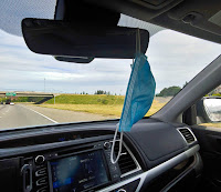 Face mask hanging from the rear view mirror of a vehicle driving on the freeway