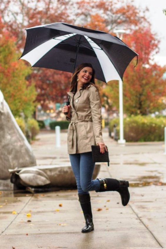 Woman with umbrella wearing jeans and rain boots