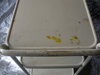 Rust stains all over the top tray of an old metal rolling cart.