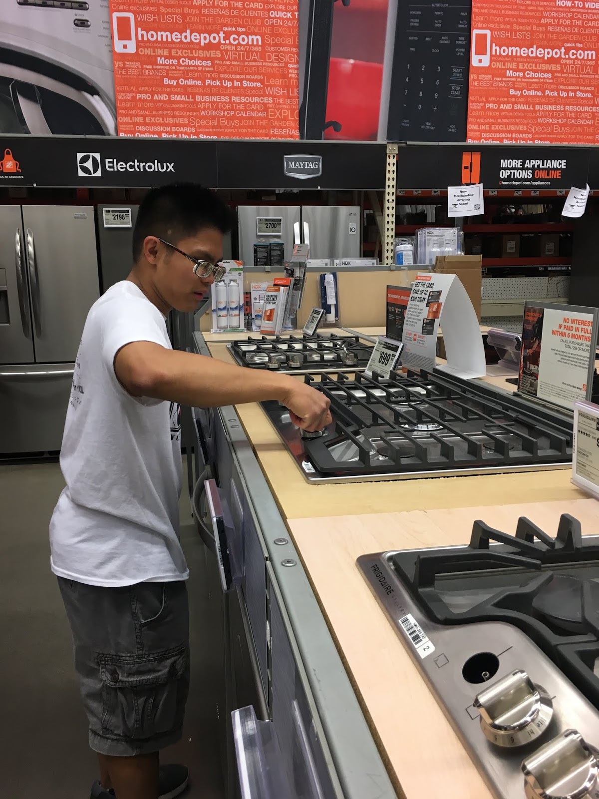 a male young adult turns the knobs on a stove as he checks it out. 