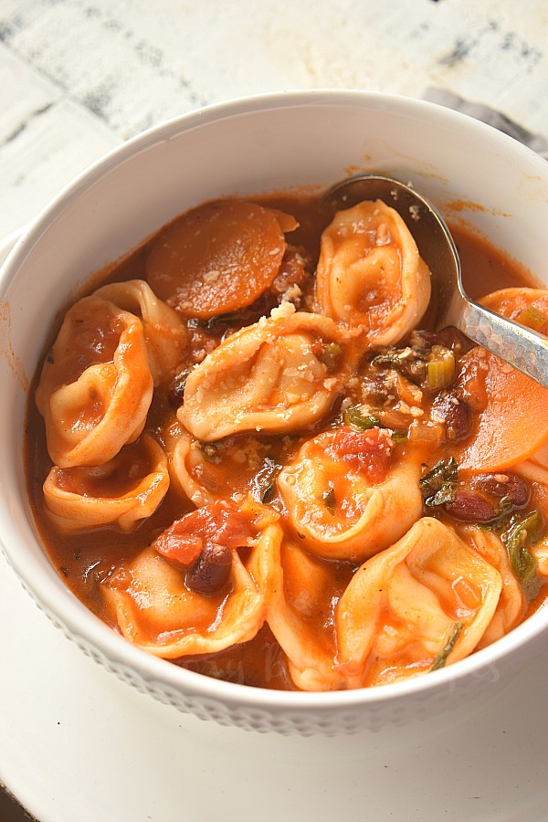 close up of white bowl with tortellini minestrone soup