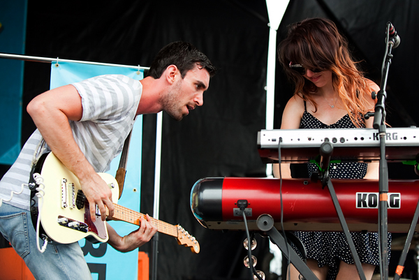 Jesse with a guitar and Suzie with music keyboard on stage