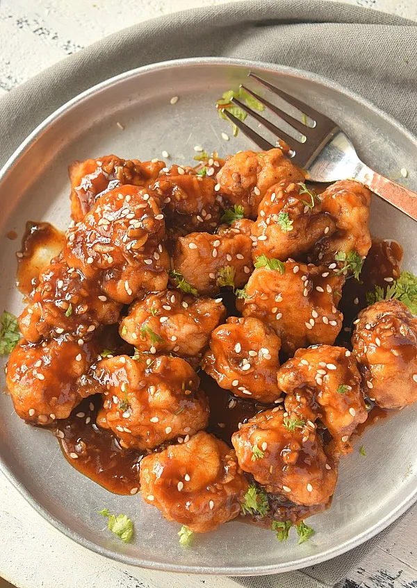 birdseye view of a plate with general tsos cauliflower sprinkled with sesame seeds
