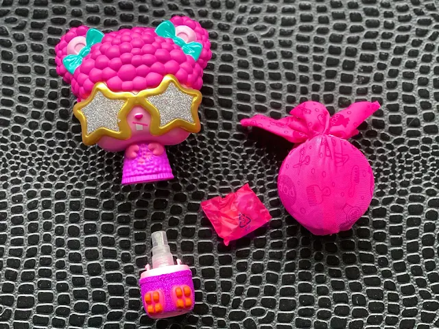 The brush separates to reveal a spray bottle and includes a pop surprise parcel and little bag with clips and bands in