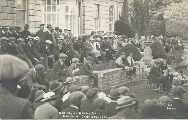Crowds seated and standing in front of a big house