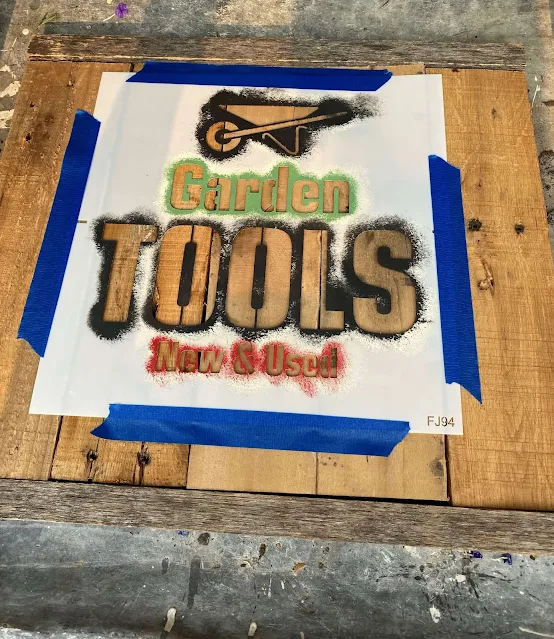 Photo of a garden tools stencil taped to a pallet sign