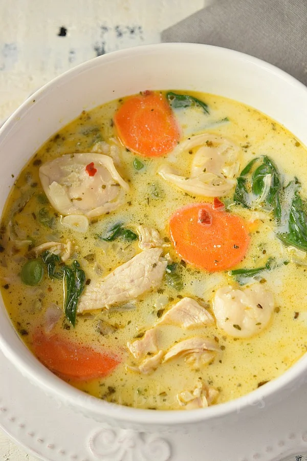 a white bowl with delicious chicken tortellini soup with veggies
