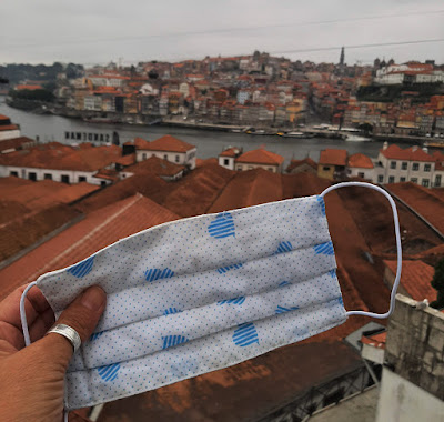 mão segurando máscara e a cidade do Porto ao fundo