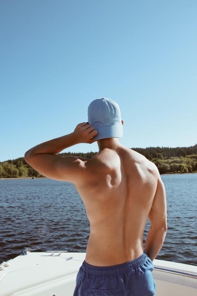 anonymous-young-shirtless-hunk-strong-back-blue-baseball-cap-shorts-boat-sightseeing-sea-view-lake-gay-cruising