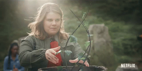 Gif: cenas das personagens Musa, com casaco vermelho, cabelos escuros presos em coques erguendo as mãos e fazendo uma energia arroxeada surgir, Aisha, uma garota negra com roupas azuis e cabelos pretos com mechas azuis-escuras, fazendo uma porção de água erguer-se entre suas duas mãos e Terra, uma garota branca, gorda e de cabelos castanho claros, com roupas verde-escuras e um casaco por cima fazendo uma planta crescer, as três estão em algum tipo de círculo de pedras em um bosque.