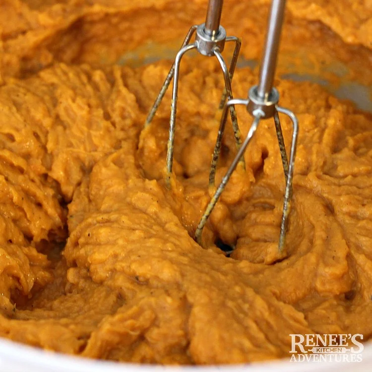 Close up of whipped sweet potatoes and two beaters from electric mixer in white bowl for Sweet Potato Souffle Casserole by Renee's Kitchen Adventures