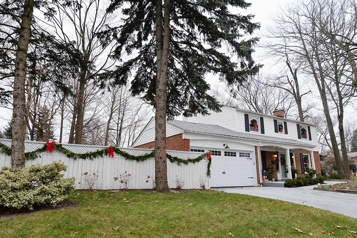 Christmas colonial house with garland on white fence
