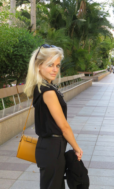 Alejandra Colomera con camiseta negra, pantalón formal negro, lazo en el cuello negro con lunares blancos y complementos mostaza