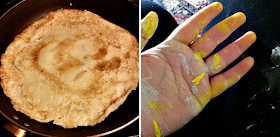 A pancake in a pan and my hand covered in grey and yellow paint.