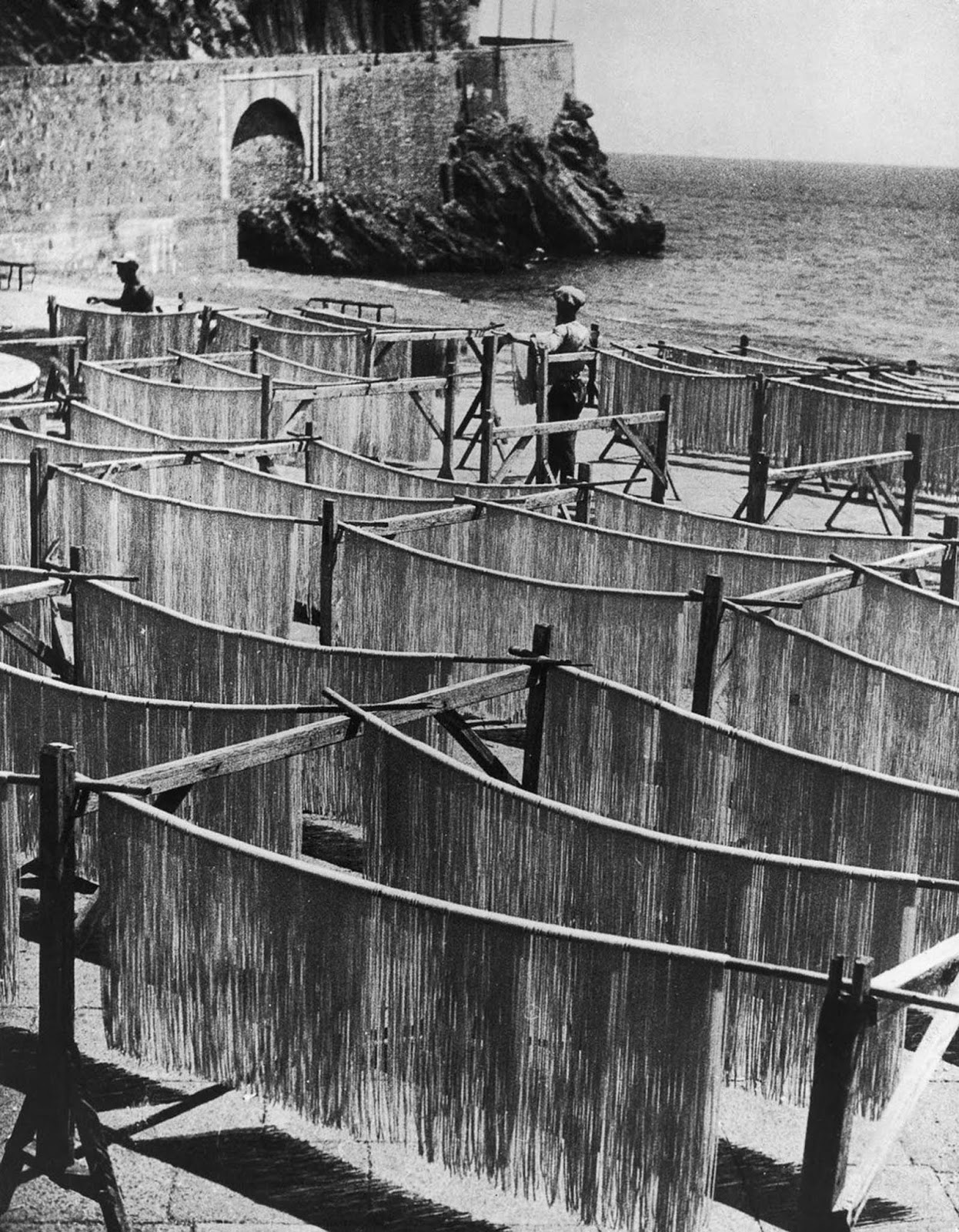 Strands of spaghetti dry on racks near the beach in Amalfi, Italy. 1949.