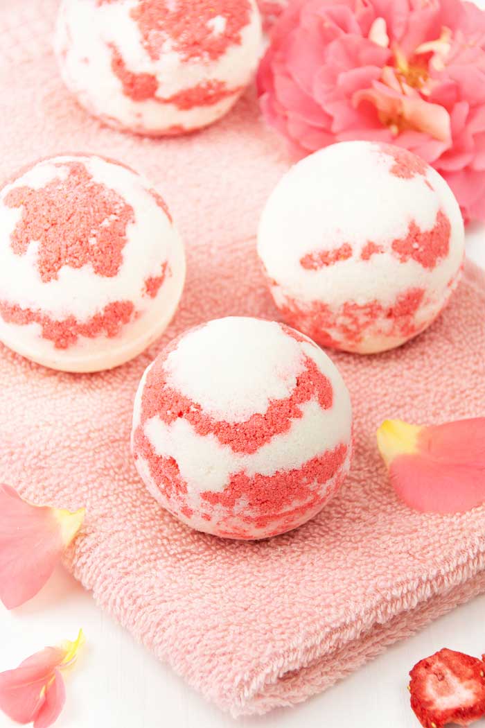 How to make a strawberry milkshake bath bomb without cornstarch. These cute and unique bath bombs would make a great gift. These natural bath bombs are fizzy and moisturizing. This DIY easy recipes uses essential oils for natural scents.  Home made pretty and cool bath bombs.  If you need ideas for summer bath bombs, try this recipe.  #bathbomb #diy #strawberry