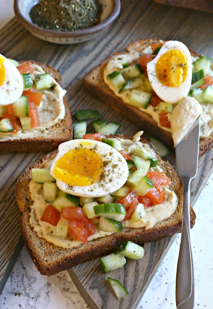 Breakfast toast with hummus, tomatoes, cucumbers and jammy eggs.