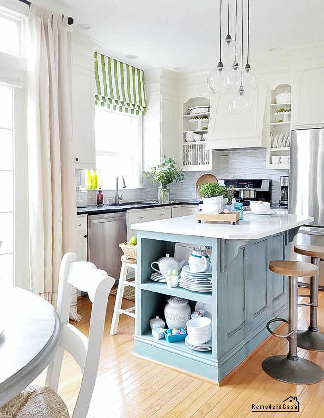 white kitchen with blue island and green shades