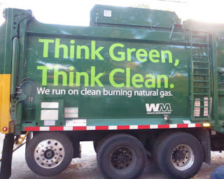 Side of green Waste Management garbage truck with huge letters reading