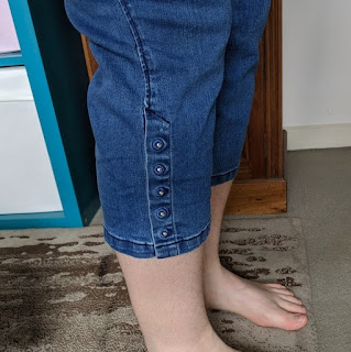 Photo of legs wearing 3/4 jeans with metal buttons on the outside seam.