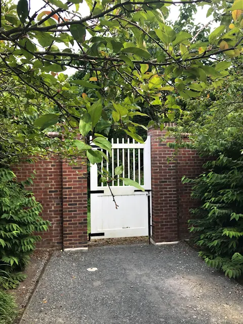 White garden gate between brick walls