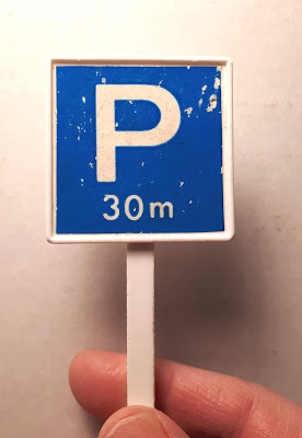 Hand holding up a vintage plastic parking sign