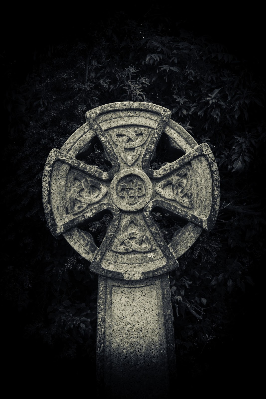 a large celtic cross grave stands in front of a black wall for blog post about the movie the boondock saints