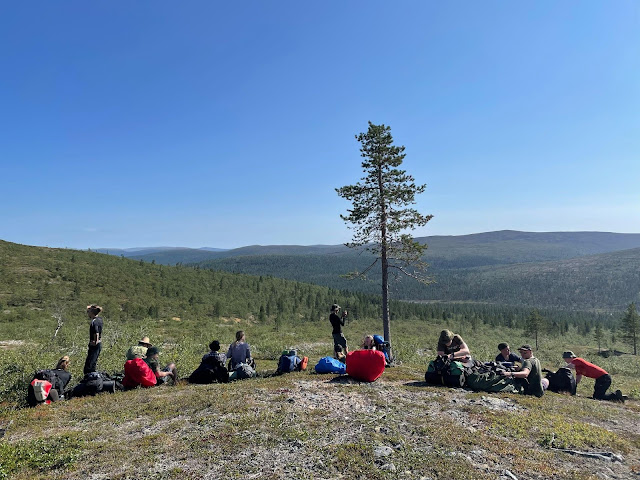 Rippikoulunuoria rinkkoineen vaelluksen tauolla tunturin rinteellä.