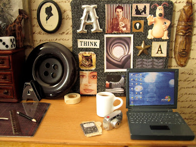 Detail of a 1/12 scale studio desktop with laptop, camera and coffee.