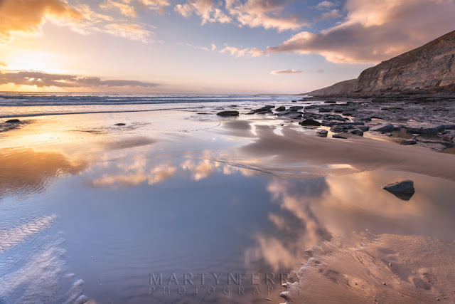 Clouds reflect in the ocean at Dunraven Bay in South Wales by Martyn Ferry Photography