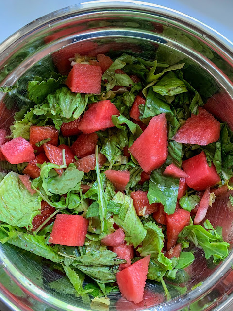 Cubes of watermelon mixed with arugula, lettuce, mint, and a balsamic dressing