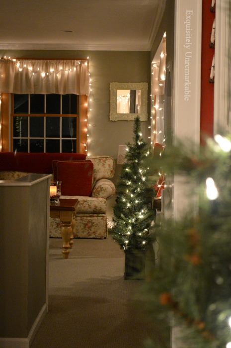 Simple Family Room Christmas Decorations with lights on the window and one small tree in an urn