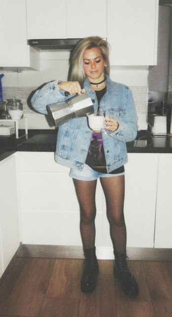 Estilo grunge con camiseta negra ancha con imagen del grupo The Doors, pantalón corto, medias de red pequeña, botas estilo militar y cazadora vaquera