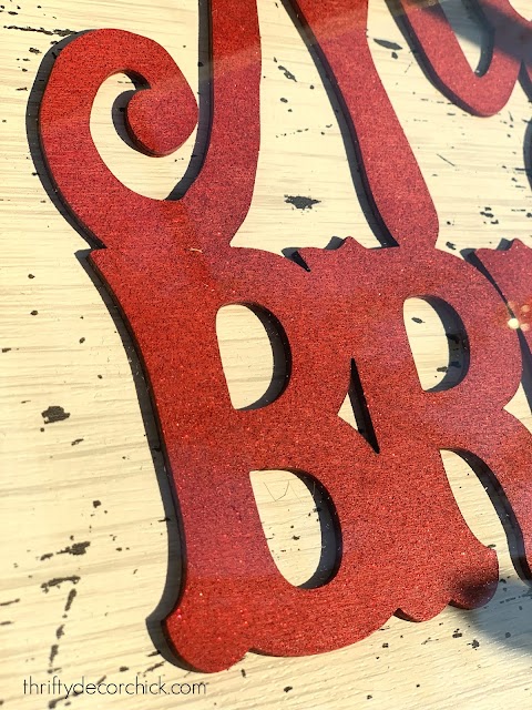 Glitter spray paint in red on wood sign