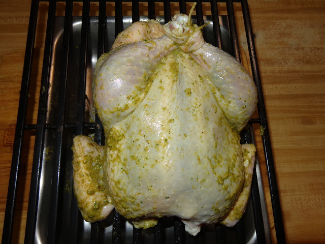PORTIONS: 4 INGREDIENTS 4 lb. whole chicken 2 cups water or chicken broth 1 cup white wine ½ cube chicken bouillon, without monosodium glutamate 2 tsp. cornstarch CHIMICHURRI PASTE SEASONING INGREDIENTS 1/4 cup chopped onions 3 garlic cloves, chopped 2 tbsp. chopped parsley ½ tsp. dried oregano leaves or 1 tsp. fresh 1½ tsp. salt ½ tsp paprika ¼ tsp ground black pepper ½ tbsp. soften butter 2 tbsp. olive oil METHOD Make the chimichurri paste placing all the ingredients in a blender. Lately it is recommended not to wash the chicken, for the risk of contamination when the water splashes on other surfaces. I’m sorry, but I rinse the chicken inside and out, with cold water. Pat dry the chicken with paper towels and place it in a dish temporarily. Then clean with soap and water the entire area of the sink or surfaces that may have been contaminated. With your fingers, separate the skin from the breast and thighs without tearing it apart. Using a teaspoon spread the ½ the chimichurri underneath the skin, around the breast and thighs. Spread the rest of the chimichurri over the chicken skin. Bend the wings under the chicken and tight the chicken legs with a kitchen twine. Pour the water and wine in a pot. Bring it to a boil and dissolve the chicken bouillon. Place the liquid in a roasting pan and put a griddle on top. Place the chicken on top of the griddle. Preheat the oven at 325°F / 163°C Roast the chicken for about 90 minutes. Baste the chicken every 20 minutes. The chicken should have a minimal internal temperature of 165°F / 74°C or if you pierce it with a skewer the juices should run clear, cook until golden brown. Pour the juices in a fat separator discard as much fat as possible. Pour the liquid in a pot and bring it to a boil. Mix the cornstarch with 1 tbsp. of water and mix it into the liquid. Let the sauce cook for 3 minutes.  Untie the legs, carve the chicken and serve with the sauce.
