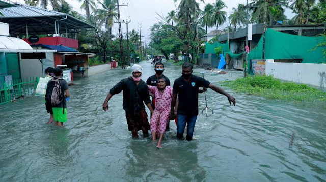 Police and rescue personnel evacuate a local resident through a flooded street in a coastal area after heavy rains under the influence of cyclone 'Tauktae' in Kochi on May 14, 2021.