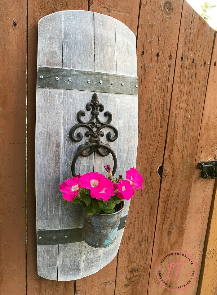A unique outdoor wall planter idea using a repurposed stave and wrought iron door knocker.