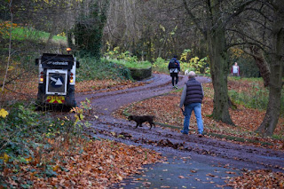 A dog walker and a cyclist in the park