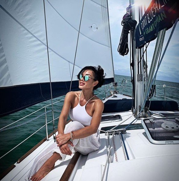 Caption: Sharon Tay sitting in a boat & enjoying traveling.