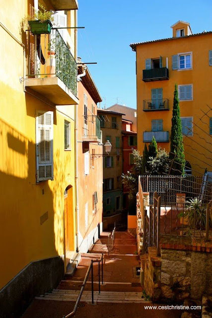 Calle angosta con escalinatas entre fachadas a color Un rincón de la Riviera francesa